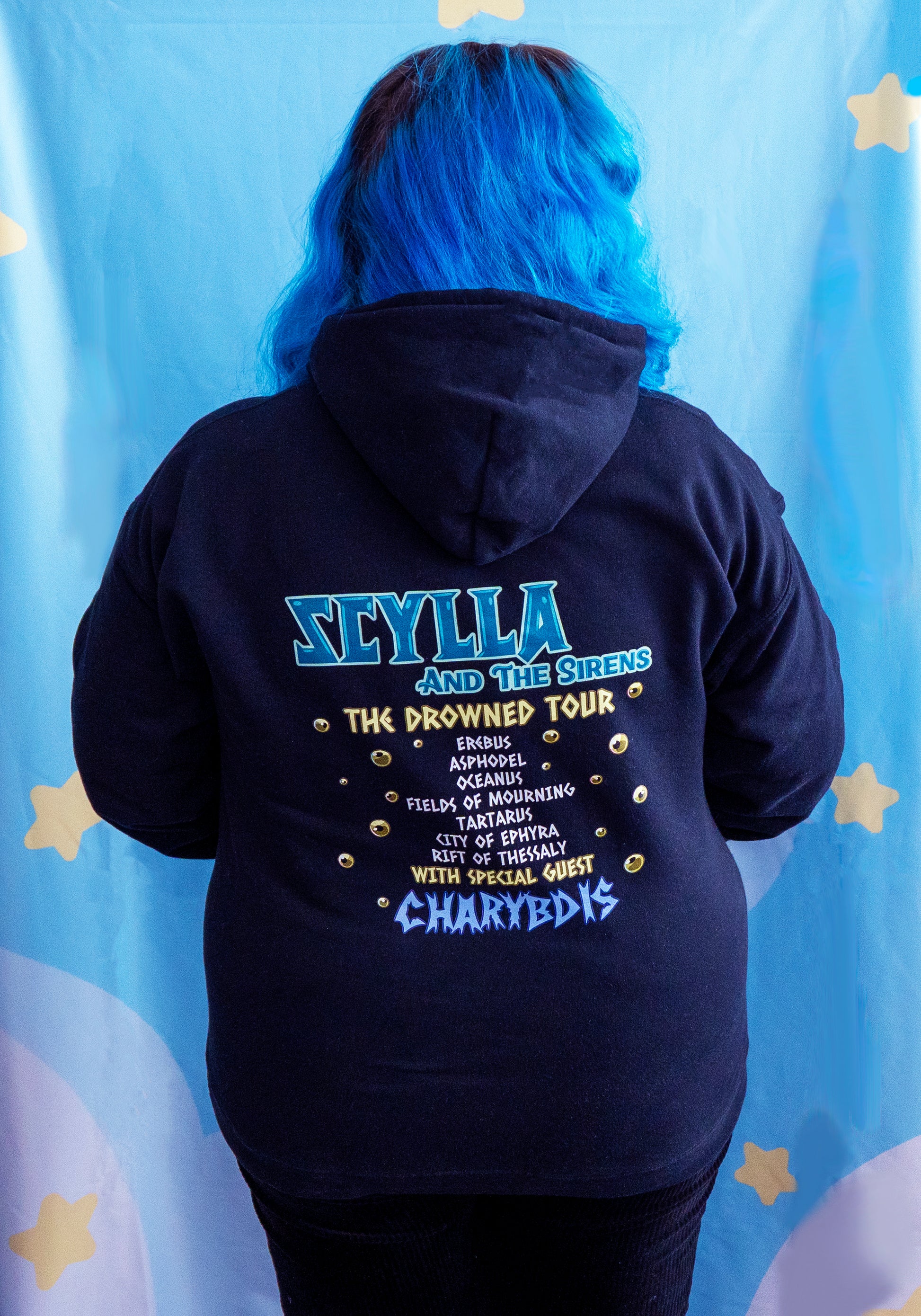 Person wearing a black hoodie with text on the back against a light blue curtain background